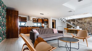 A modern living room with a sofa, two chairs, a coffee table, and a kitchen in the background. - Casa Azul (Panama City)