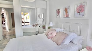 Ein modernes Schlafzimmer mit einem großen Bett, Nachttischen und Kunstwerken an den Wänden.
