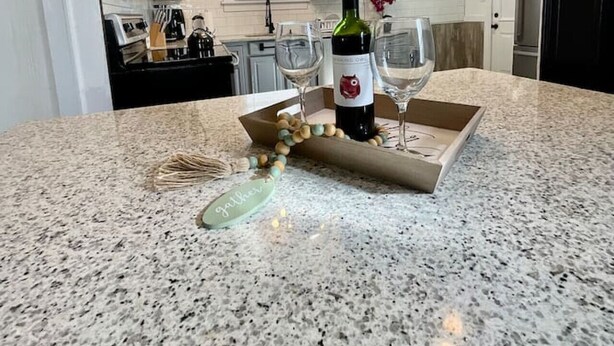 A kitchen with a granite countertop, a wine bottle, and a decorative item. - Relax with the whole family at this peaceful place to stay. (Columbus)