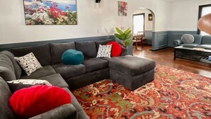 A living room with a gray sectional sofa, a red and orange patterned rug, and a ceiling fan. - Relax with the whole family at this peaceful place to stay. (Columbus)