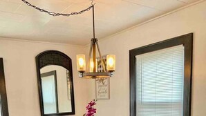 A dining area with a wooden table set for four, surrounded by chairs. A chandelier hangs above, and a mirror is mounted on the wall. - Relax with the whole family at this peaceful place to stay. (Columbus)