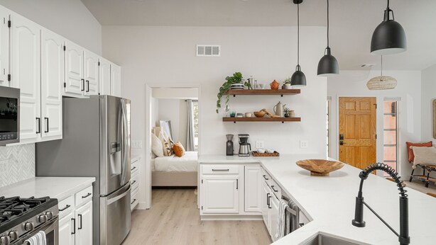 Una cocina moderna con armarios blancos, electrodomésticos de acero inoxidable y una isla central.