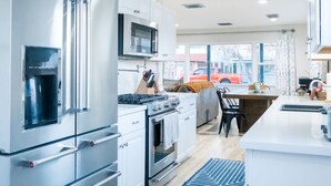 Een moderne keuken met roestvrijstalen apparatuur, een centraal eiland en uitzicht op de straat.