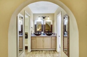 A bathroom with a double vanity, a large mirror, and a tiled floor.