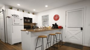A modern kitchen with white cabinets, a central island with stools, a microwave, a toaster, and a coffee maker. - Escape to Beech Mtn-0.6 mi to Ski Lodge-Walkable (Beech Mountain)