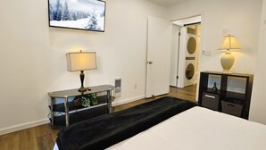 A bedroom with a bed, a desk with a lamp, a wall-mounted TV, and a door leading to a laundry area. - Escape to Beech Mtn-0.6 mi to Ski Lodge-Walkable (Beech Mountain)