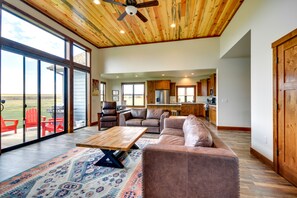 Relax in this spacious living area with a high ceiling, featuring a large leather sofa and armchair, and a wooden coffee table.