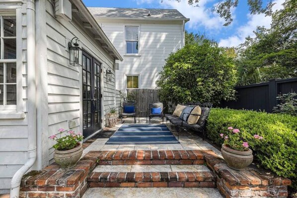 Step onto the inviting front porch, where a cozy seating area awaits with a sofa and small table.