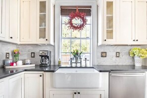 Kitchen with a central sink, cabinetry, and a coffee maker.
