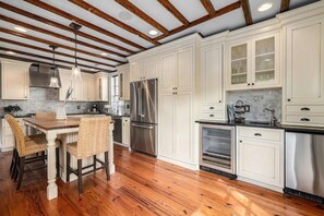 Enjoy cooking in this classic kitchen with white cabinetry, glass-fronted upper cabinets, a stainless steel refrigerator, and oven.