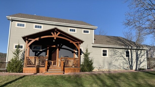A two-story house with a covered porch and a small deck. - CREEKSIDE RETREAT 5 miles from Cooperstown, NY. (Hartwick)