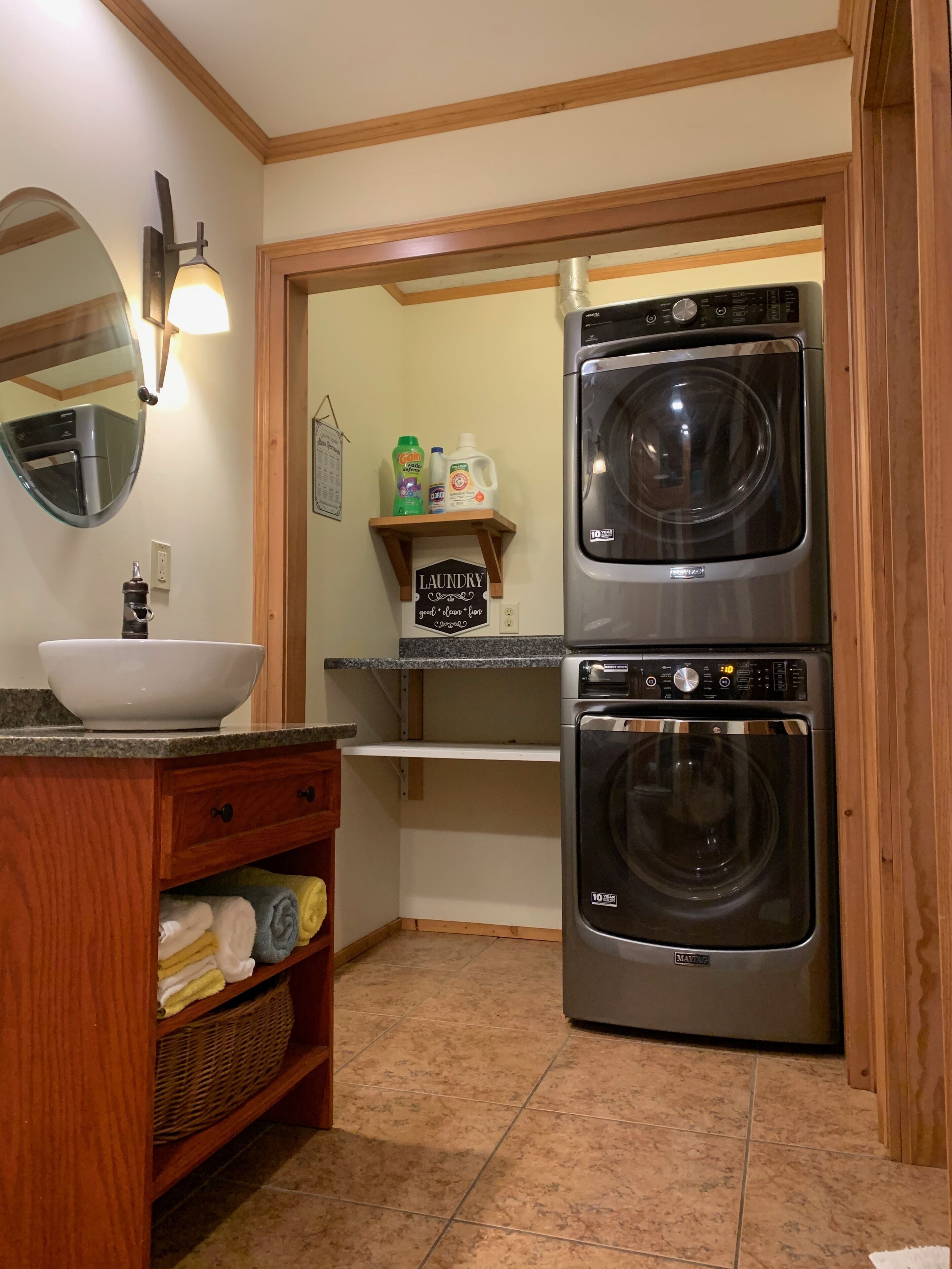 A compact laundry room with a washing machine and dryer, a sink with a bowl, and a mirror.