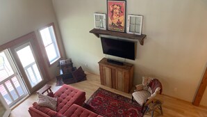 A living room with a red sofa, a patterned rug, a wooden cabinet, and a television. - CREEKSIDE RETREAT 5 miles from Cooperstown, NY. (Hartwick)