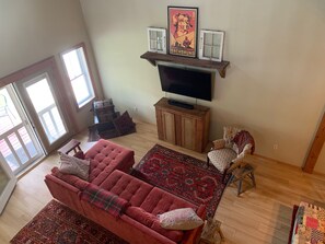 A living room with a red sofa, a patterned rug, a wooden cabinet, and a television.