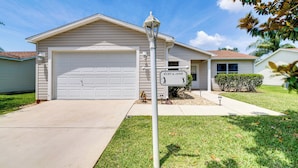 A single-story house with a garage, a well-maintained lawn, and a street lamp. - Complimentary Golf Cart! Home in The Villages (The Villages)