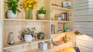 A wooden shelving unit with various plants, books, and a lamp.