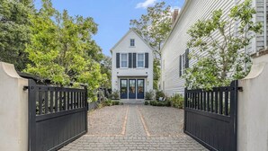 A two-story house with a central entrance, flanked by black gates, and surrounded by trees. - Downtown Charleston! One block to King St. Free parking for two vehicles (Charleston)