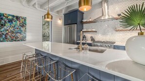 A modern kitchen with a central island, bar stools, stainless steel appliances, and a decorative plant. - Downtown Charleston! One block to King St. Free parking for two vehicles (Charleston)