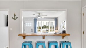 A kitchen with a wooden countertop, blue bar stools, a ceiling fan, and a view of a car through a window. - Cozy Coleman-Families- Near Beaches, Airport & PCC (Pensacola)