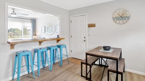 A kitchen with a wooden countertop, three blue stools, a wooden table with a bench, and a wall clock. - Cozy Coleman-Families- Near Beaches, Airport & PCC (Pensacola)