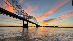 Un pont enjambant une étendue d’eau, avec un coucher de soleil en arrière-plan.
