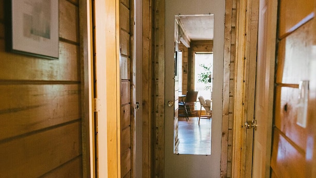 A wooden hallway with a door at the end leading to a room with a window.