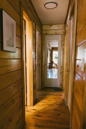 Ein Holzbodenkorridor mit einer Tür am Ende, die in einen Raum mit einem Fenster führt.