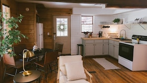A cozy kitchen with wooden walls, a dining area with a table and chairs, and a modern stove.