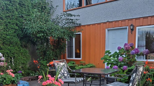 An outdoor patio area with a table and chairs, surrounded by flower planters and a wooden fence.