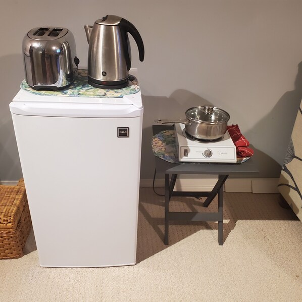 Une petite cuisine équipée avec un réfrigérateur blanc, une bouilloire, un grille-pain et une plaque de cuisson portable.