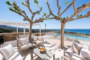An outdoor seating area with a pool, stone walls, and a view of the sea.