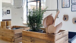 Moderni sisustus, jossa on puiset kukkaruukut, riippuvalaisin ja seinälle ripustetut kehystetyt kartat.