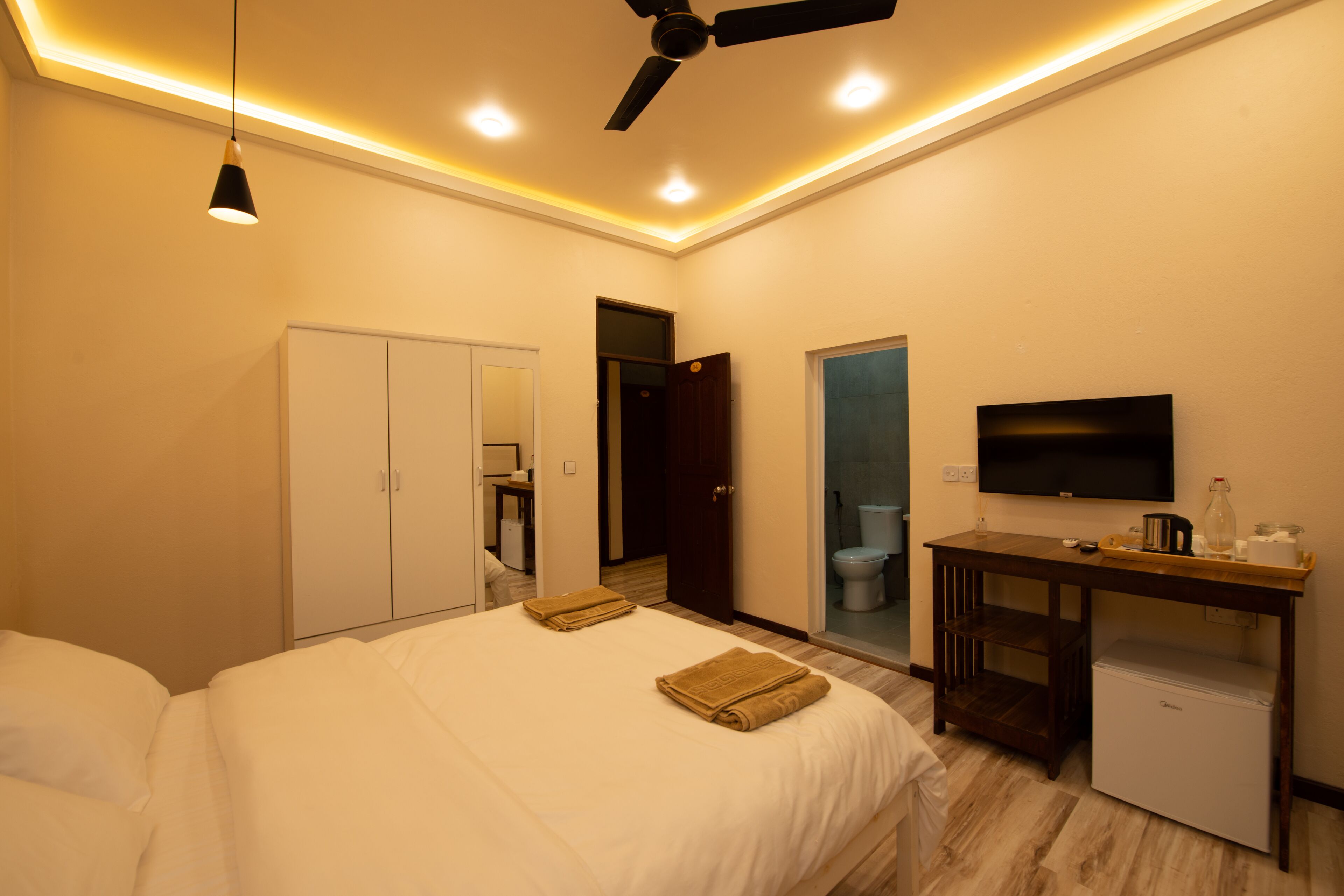 A hotel room with a bed, a desk, a television, and a wardrobe.