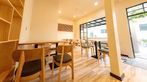 A modern interior with wooden furniture, a patterned wall, and large windows. - The Bilimbi Guesthouse and Inn (Huraa)