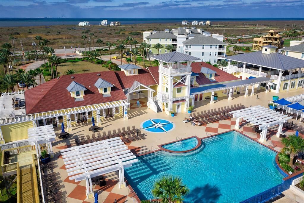 A resort with a swimming pool, lounge areas, and a view of the ocean.