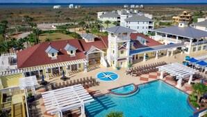 A resort with a swimming pool, lounge areas, and a view of the ocean.