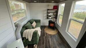 A cozy room with a green sofa, a fireplace, and a view of the outdoors. - Tiny Home, Lake View, RV & Boat Parking, Pistol Range. (davenport)