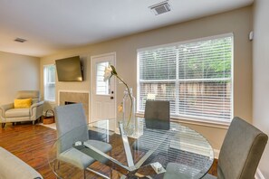 A living room with a glass table, two grey chairs, a sofa, and a fireplace. - Modern Woodlands Townhome w/ Spacious Yard & Patio (The Woodlands)
