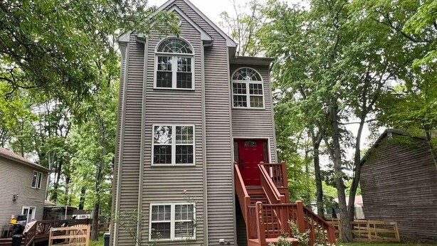 A two-story house with a red door and a small porch. - Entire house on quiet street w/fenced yard—1 block from river, 3 from bay (Annapolis)