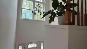 A staircase with wooden balusters, a white door with a stained glass window, and a hanging plant. - Entire house on quiet street w/fenced yard—1 block from river, 3 from bay (Annapolis)