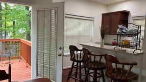 A kitchen with a wooden island, a dining area with chairs, a view of the outdoors, and a sliding glass door. - Entire house on quiet street w/fenced yard—1 block from river, 3 from bay (Annapolis)