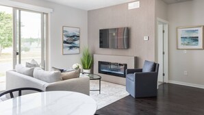 Un salon moderne avec un canapé, un fauteuil et une table basse en verre.