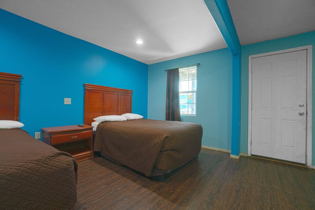 A hotel room with a large bed, a bedside table, a wardrobe, and a window with curtains.