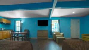 A room with blue walls, wooden furniture, a flat-screen TV, and a door. - Plaza Motel Corpus Christi By Oyo (Corpus Christi)