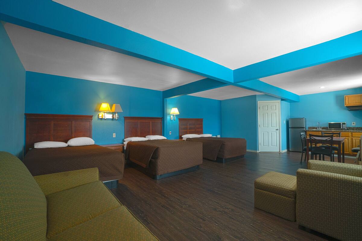 A hotel room with two beds, a kitchenette, and a seating area.