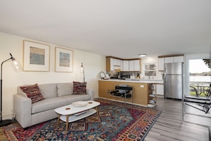 Un apartamento moderno con sofá, mesa de centro, zona de cocina y vistas al exterior.