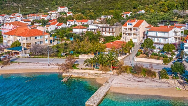 An aerial view of a coastal town with buildings, a beach, and a clear blue sea. - Villa Ponar with Swimming Pool (Kuciste)