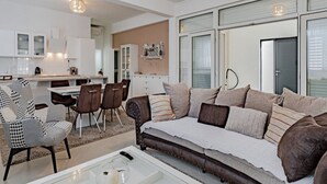A modern living room with a sofa, chairs, a coffee table, and a kitchen area in the background. - Villa Ponar with Swimming Pool (Kuciste)