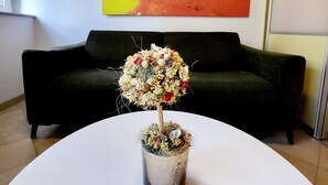 A potted plant with a unique design on a white table in a room with a black sofa and a colorful painting on the wall. - Green Terrace Apartment I (Dubrovnik)