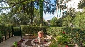 A garden with a stone pathway, potted plants, and a green gate. - Green Terrace Apartment I (Dubrovnik)